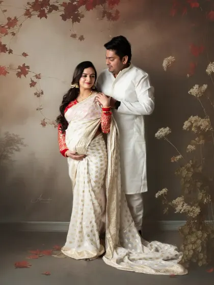A classic couple's portrait in coordinated white and red traditional outfits. Their pose is full of grace and mutual affection.