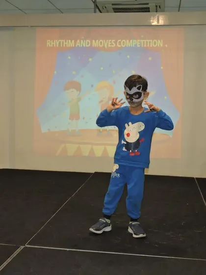 A young performer in a mask strikes a pose during the 'Rhythm and Moves' competition, a platform designed to build stage presence.