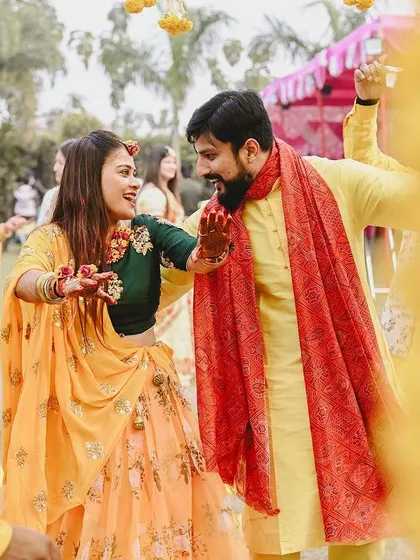 A candid shot of the couple dancing together at their Haldi event, framed by marigold garlands.