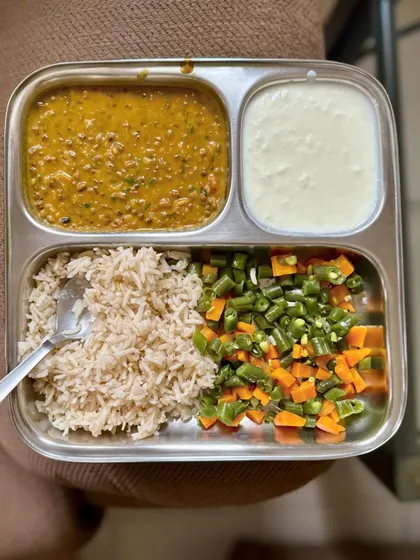 A wholesome plate of brown rice, dal, sautéed mixed vegetables, and curd.