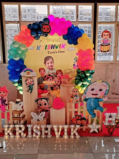 We set up this delightful Cocomelon theme for Krishvik's first birthday party. It features a rainbow balloon arch, multiple character cutouts, and a light-up name sign, creating a cheerful and inviting atmosphere for the celebration.