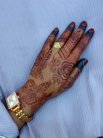 A single-hand view of a detailed party henna design. The pattern combines floral elements with traditional motifs on the fingers, and the stain is a consistent, rich brown.