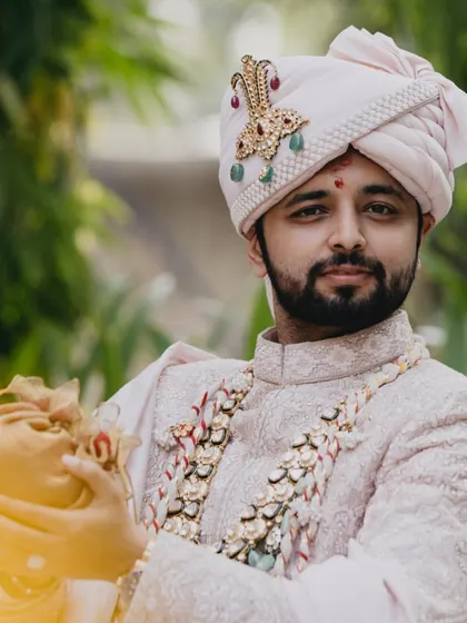 A portrait of the handsome groom, ready for his wedding, holding the traditional 'shreefal'.