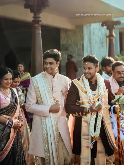 The groom's entrance, surrounded by smiling family members. This shot captures the pride and happiness of the family during the wedding procession.