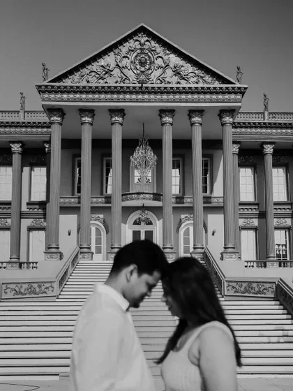 A black and white portrait in front of a grand, palatial building. The classic composition and monochrome edit give this modern location a timeless, romantic feel.