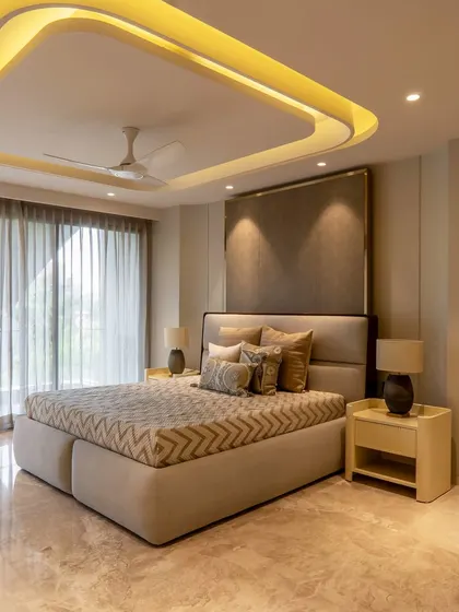 This bedroom features a unique curved ceiling with integrated cove lighting, creating a soft, ambient glow. The design uses a minimalist approach with earthy tones to craft a tranquil and modern retreat.