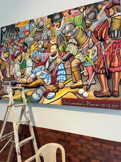 The mural during installation, with a ladder nearby, giving a sense of the large scale of this artwork.
