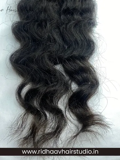 A close-up of the texture of our I-Tip Raw Curly Hair Extensions. You can see the natural curl pattern, which is unprocessed to maintain its integrity and bounce.