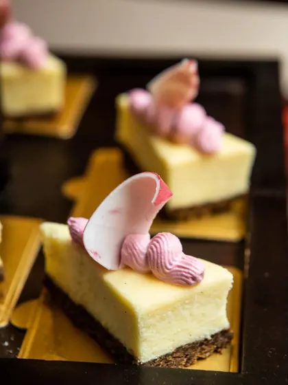 Slices of delicate cheesecake topped with pink frosting and an edible flower petal.