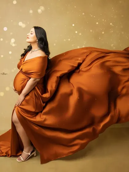 This dramatic solo portrait showcases our flying fabric technique. The rich, rust-colored gown billows out, creating a sense of movement and grace against a warm, glowing backdrop.
