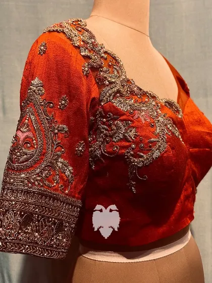 A close-up of the orange blouse, showing the delicate paisley and embossed sleeve designs.