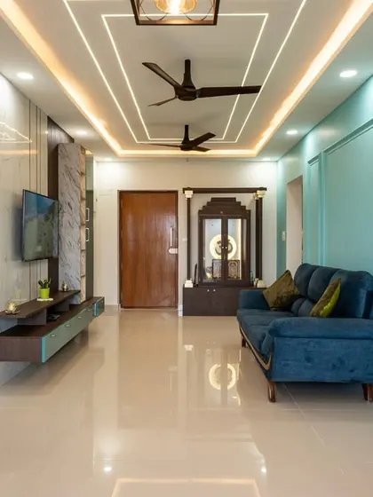 This view highlights the cohesive design of the living space, from the teal wall and floating TV unit to the false ceiling design, creating a modern and luxurious feel.
