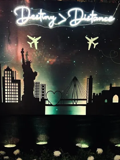 A creative and personal photo backdrop that tells the couple's long-distance love story, from New York to Mumbai. The neon sign 'Destiny > Distance' is a perfect touch.