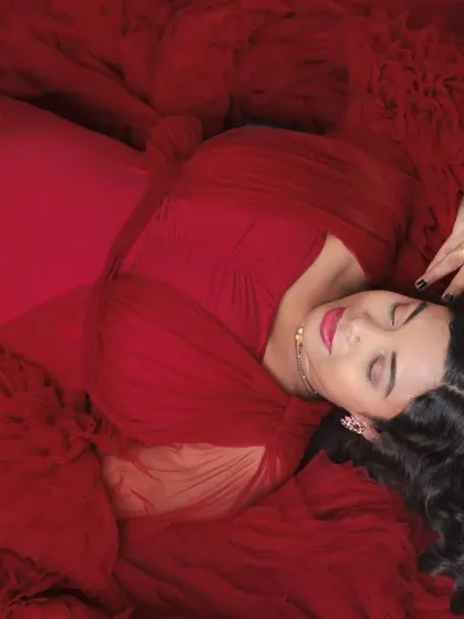 A unique top-down portrait of a mother-to-be lying on a bed of red fabric. This artistic angle and bold color choice result in a highly creative and memorable photo.