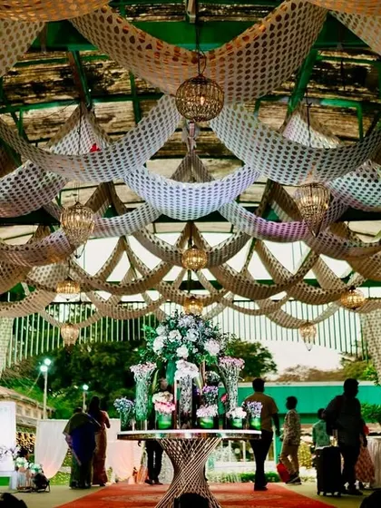 An elegant event hall entrance with a ceiling of intricate white netting and hanging lanterns, creating a sophisticated welcome.