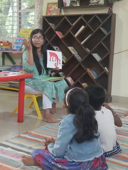 The storyteller uses a visual aid to represent the red chameleon, making the story more concrete for young minds.