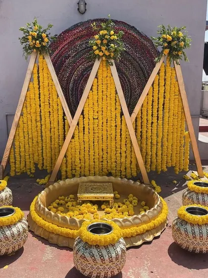 A vibrant and traditional Haldi ceremony setup. The bright yellow marigolds, rustic pots, and A-frame backdrop create a joyful and picture-perfect space for this important pre-wedding ritual.