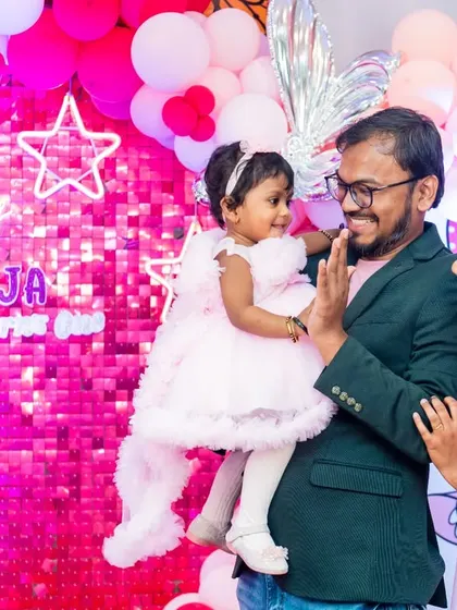 A high-five for the birthday girl. This adorable interaction between the father and his one-year-old daughter is a perfect candid moment captured during her party.