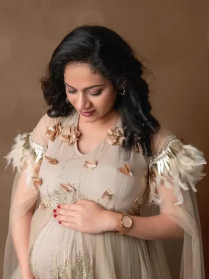 A close-up portrait in our beige gown with delicate feather and floral shoulder details, showcasing its unique and elegant design.