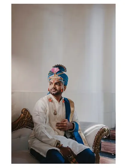 A candid portrait of the groom seated, bathed in beautiful natural window light. It's a quiet, thoughtful moment.
