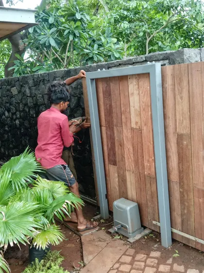 On-site in Alibaug, this image shows the installation of a wooden gate. It is a snapshot of the detailed craftsmanship and coordination required to execute design elements that blend natural materials with structural frames.
