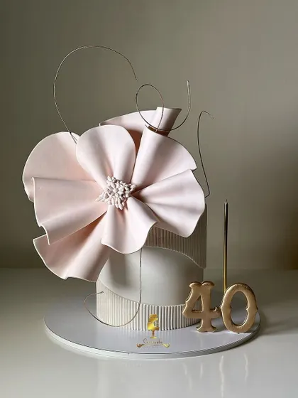 A modern and abstract cake for a 40th birthday. This design features a large, sculptural wafer paper flower and artistic wire details.