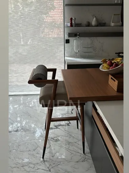 Another view of the custom barstool, showing the comfortable leather seat and the unique cylindrical backrest in a patterned fabric.