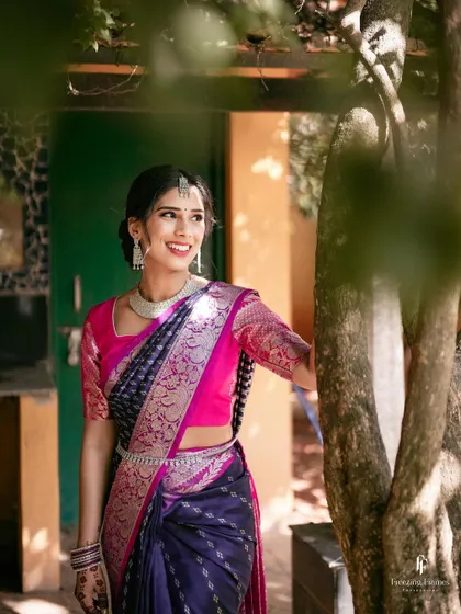 A joyful bride in a bright pink and navy saree, her happy expression lighting up the frame.