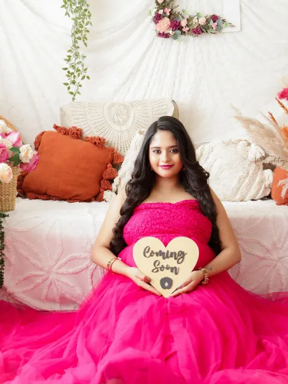 "Coming Soon." A sweet announcement photo from this mama-to-be, seated in a vibrant pink gown in a beautiful boho setting.