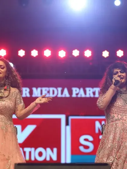 Singing together under the bright lights of the Navratri stage. Our chemistry as sisters is a huge part of our performance.