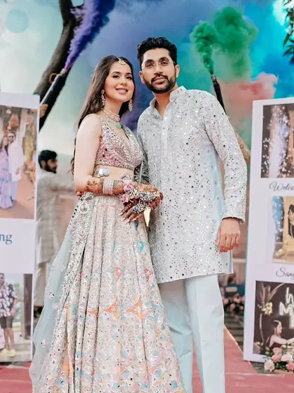 The couple makes a grand entrance at their Mehendi, framed by colorful smoke bombs and personalized photo panels that tell their love story.