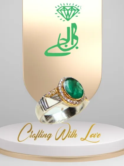 This ring is a perfect example of classic elegance. A beautiful green emerald is set in a two-tone band of silver and 18k gold, surrounded by a delicate halo of diamonds. It's a design that is both opulent and refined.