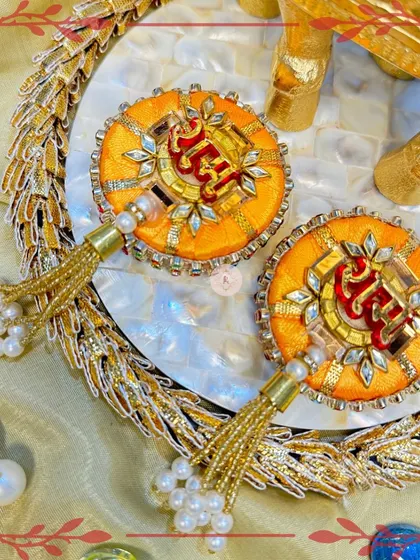 A closer look at the orange "Ram Ram" designs, highlighting the detailed threadwork and stone embellishments.