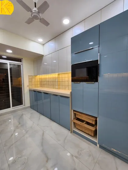 A view of the tall unit in the blue kitchen, with an integrated microwave and pull-out wicker baskets.