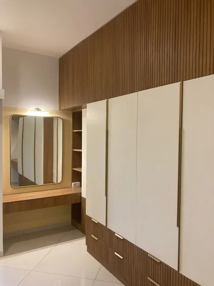 When minimalism meets ‘I still have too much stuff.’ This wardrobe combines clean white doors with wood-paneled sections and a built-in vanity.