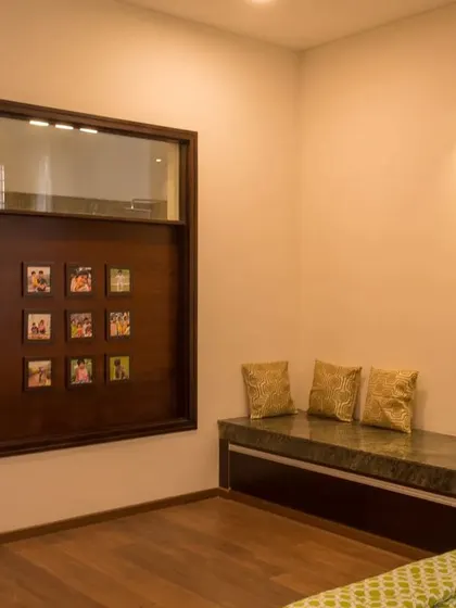 A cozy reading nook with built-in seating and storage, featuring a custom wood panel with a grid for displaying family photos.