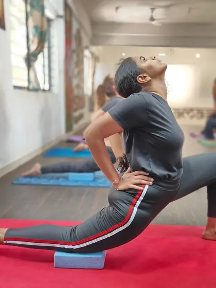 A student holds a low lunge, a pose that stretches the hips and grounds the energy.