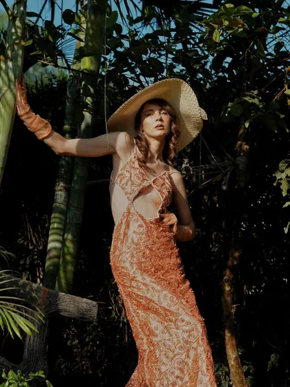 A full-length shot of the peach gown, using the natural lines of the bamboo trees to frame the model and create a dynamic composition.