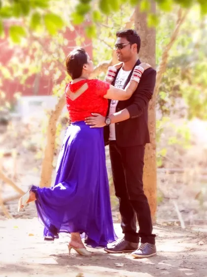 A full-length shot of a couple in a playful dance-like pose during their outdoor pre-wedding photoshoot.