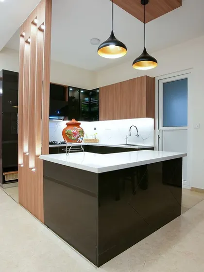 The kitchen for Palak and Ashwani features a modern island, sleek dark cabinetry, and a wooden partition with integrated lighting that elegantly separates it from the dining area.