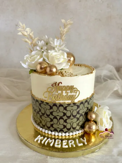 Luxury you can taste. A Coach-inspired cake for a fashion-forward birthday, featuring the brand's iconic pattern and elegant white and gold floral accents.