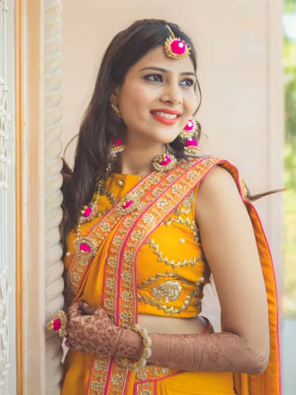 A portrait of a bride dressed for her Haldi ceremony. Her bright yellow saree and pink floral jewelry create a look that is both traditional and incredibly cheerful.