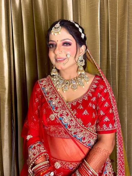 A happy bride smiling for the camera. Her makeup features a classic red lip and shimmery eyes, a timeless choice for any bride.