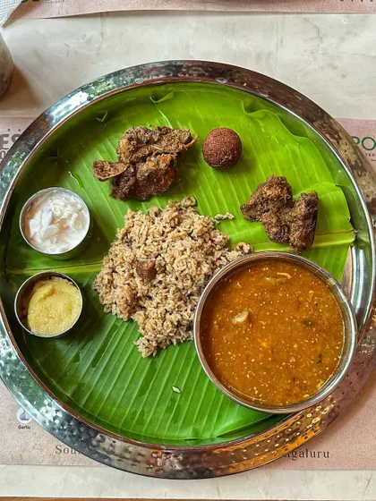 A complete Naati style meal featuring mutton palav, fried starters, and flavourful curries, all served on a traditional banana leaf.
