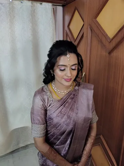A client looking serene and elegant, with a simple twisted updo that complements her lavender saree.