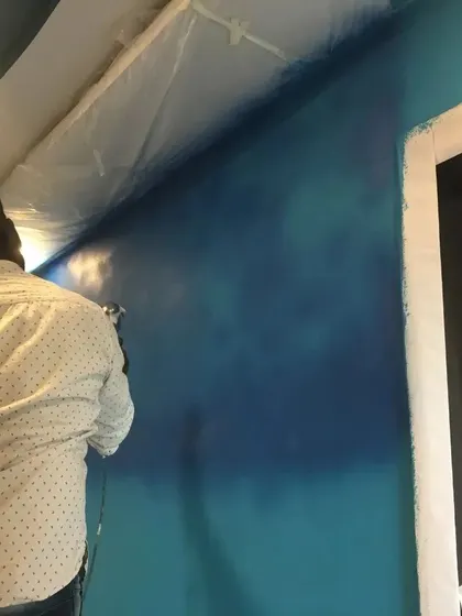 An artist from our team begins a large spray paint mural. We take care to protect the surrounding area before applying the base layers of color with an airbrush.