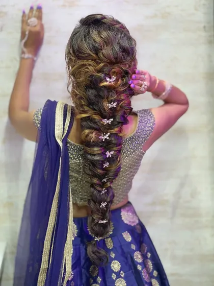 A full back view of the intricate messy braid, adorned with small butterfly clips. This style requires a mastery of braiding techniques to create its full, textured appearance.