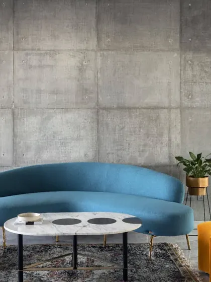 This second-floor lounge in Swatantra Residence is a brilliant combination of industrial edge and vibrant comfort. The exposed concrete walls provide a minimalist backdrop for the colorful sofa and poufs.