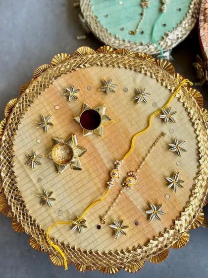 A festive yellow and gold Rakhi thal adorned with star-shaped embellishments, perfect for a joyous celebration.