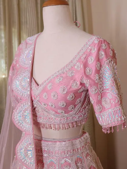 A close-up of the pink lehenga's blouse, highlighting the intricate sequin and thread work. The craftsmanship is what makes my pieces special.